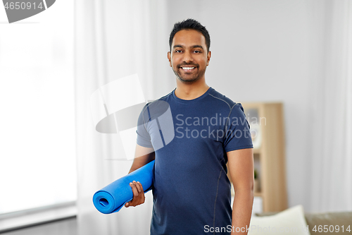 Image of smiling indian man with exercise mat at home