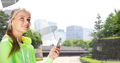 Image of woman listening to music on smartphone at city