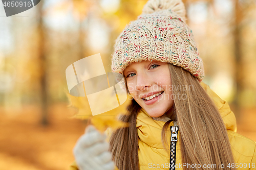 Image of portrait of girl with maple leaf at autumn park