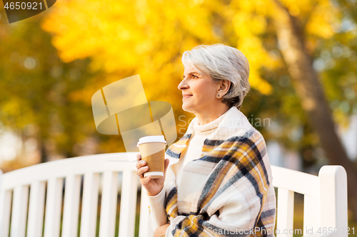 Image of senior woman drinking coffee in autumn park