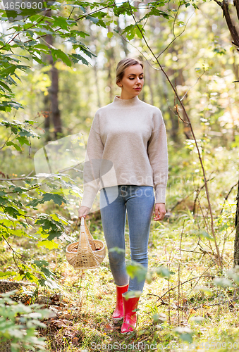 Image of woman with basket picking mushrooms in forest