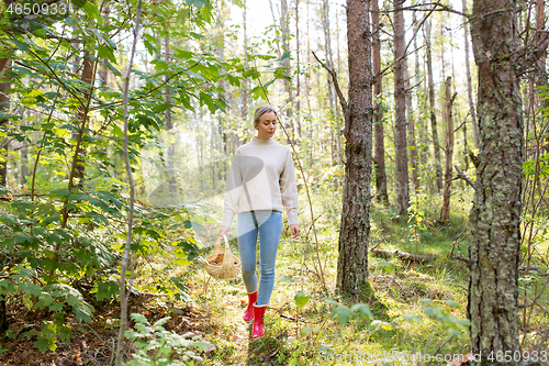 Image of young woman picking mushrooms in autumn forest