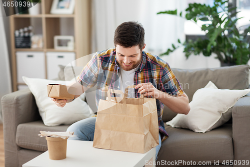 Image of smiling man unpacking takeaway food at home