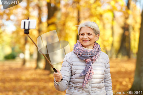 Image of senior woman taking selfie at autumn park