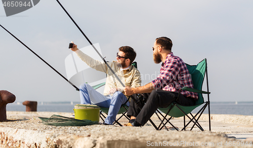 Image of friends fishing and taking selfie by smartphone