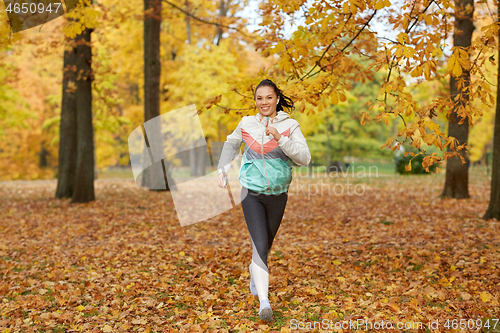 Image of woman running in park and listening to music