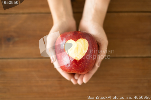 Image of close up of hands holding apple with carved heart