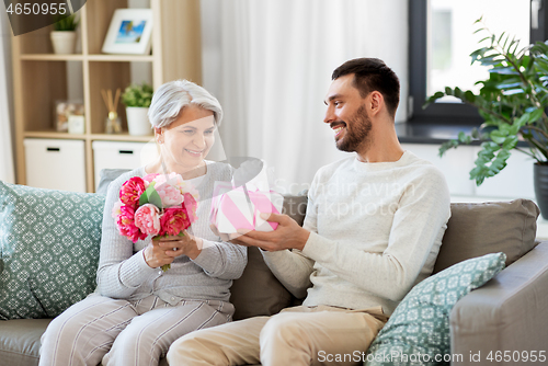 Image of son giving present and flowers to senior mother