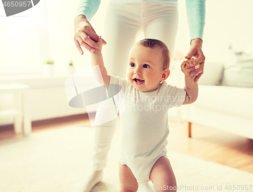 Image of happy baby learning to walk with mother help