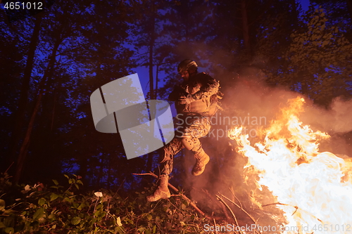 Image of Soldier in Action at Night jumping over fire