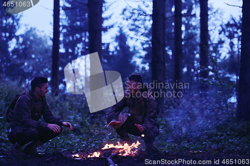 Image of soldiers resting by fire in forest