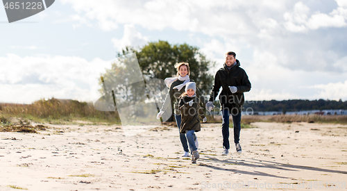 Image of happy family running along autumn beach