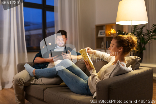 Image of couple with tablet computer and book at home