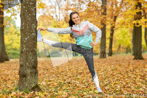 Image of young woman doing sports at autumn park