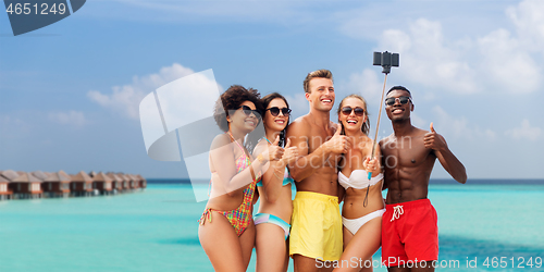 Image of friends taking selfie on beach and show thumbs up