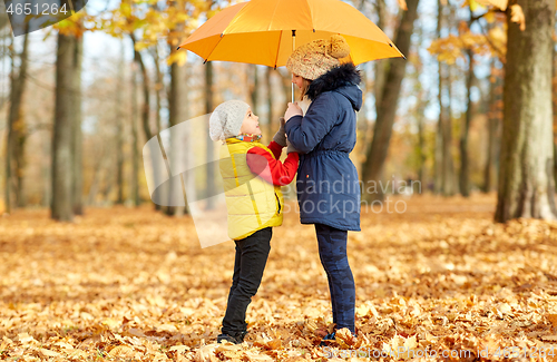 Image of happy children with umbrella at autumn park