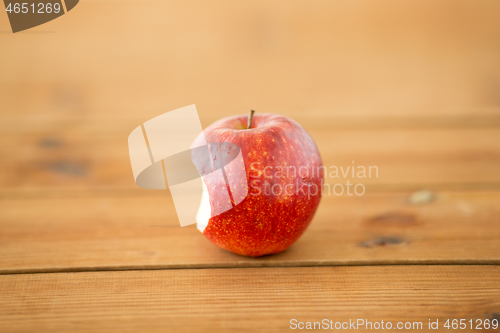 Image of ripe red bitten apple on wooden table