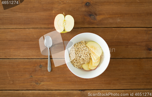 Image of oatmeal in bowl with apple and spoon on table