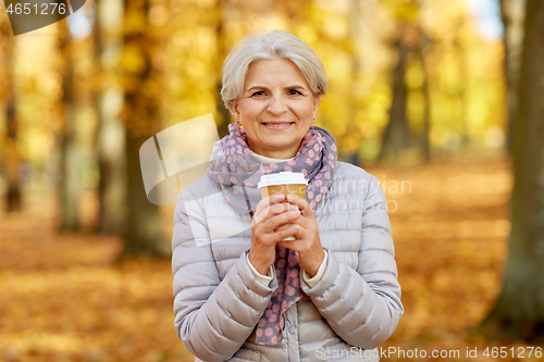 Image of senior woman drinking coffee in autumn park