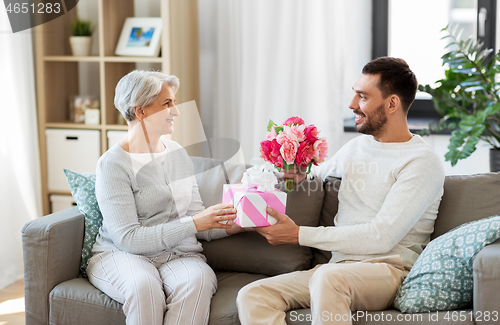 Image of son giving present and flowers to senior mother