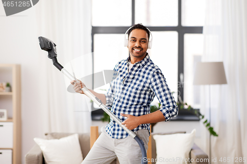 Image of man in headphones with vacuum cleaner at home