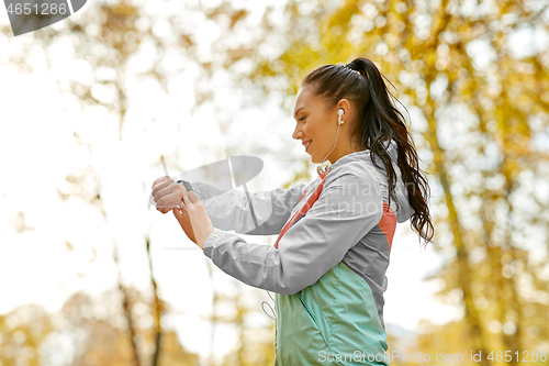 Image of woman looking at fitness tracker in autumn park