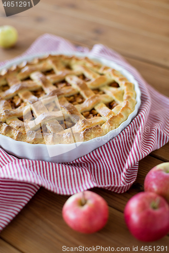 Image of apple pie in baking mold on wooden table