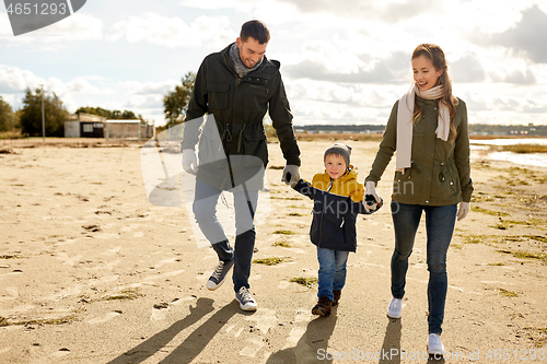 Image of happy family walking along autumn beach