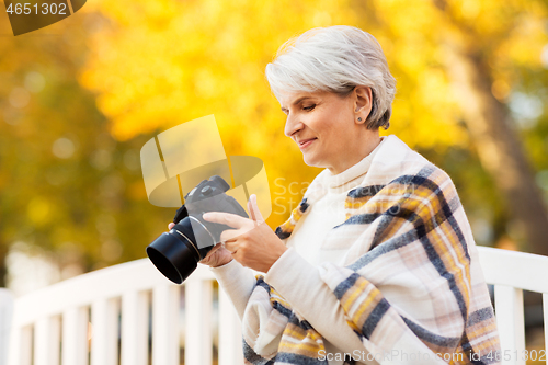 Image of senior woman with photo camera at autumn park