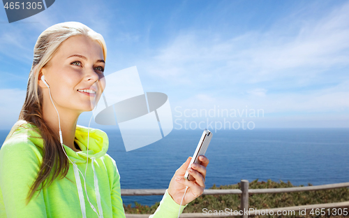 Image of woman listening to music on smartphone at seaside