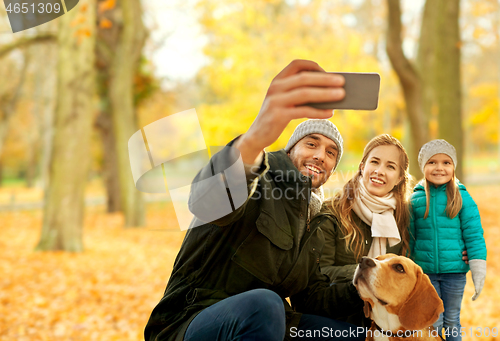 Image of happy family with dog taking selfie in autumn park