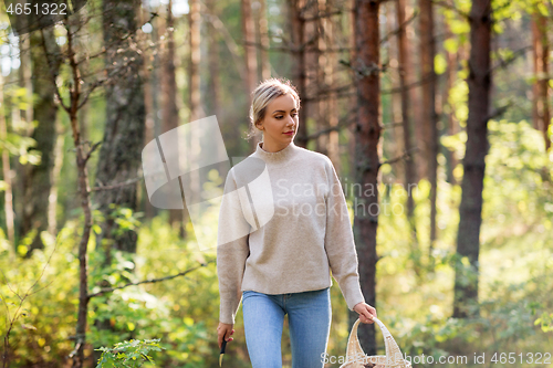 Image of woman with basket picking mushrooms in forest