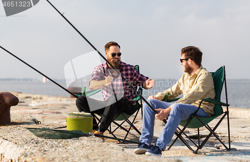 Image of happy male friends with rods talking about fishing