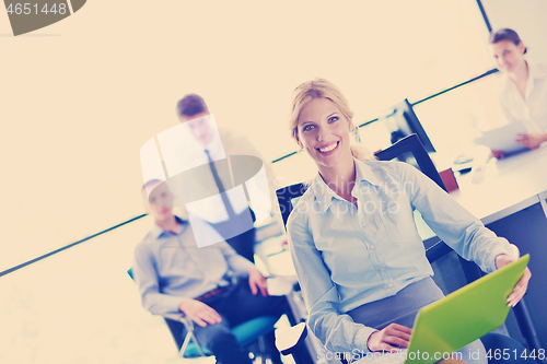 Image of business woman with her staff in background at office