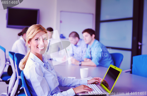 Image of business woman with her staff in background at office