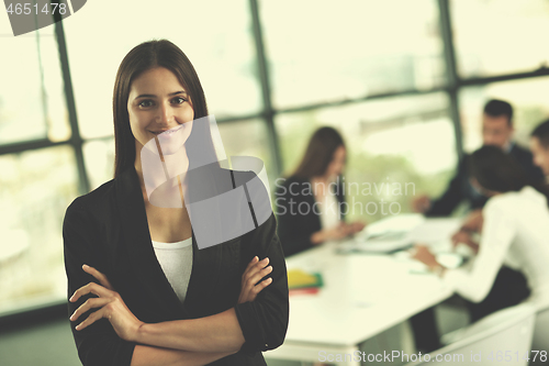 Image of business woman with her staff in background at office