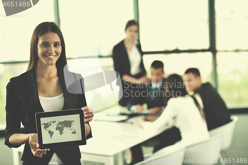 Image of business woman with her staff in background at office