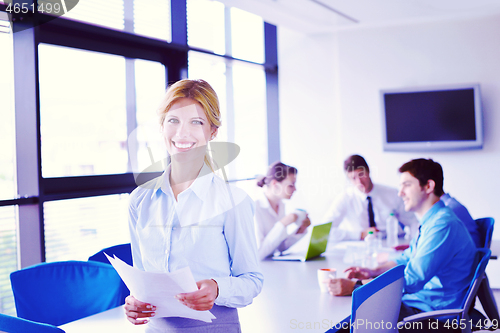 Image of business woman with her staff in background at office