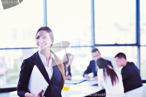 Image of business woman with her staff in background at office