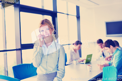 Image of business woman with her staff in background at office