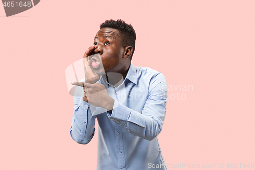 Image of The young man whispering a secret behind her hand over pink background