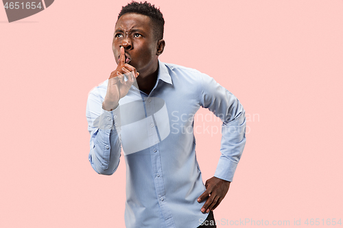 Image of The young man whispering a secret behind her hand over pink background