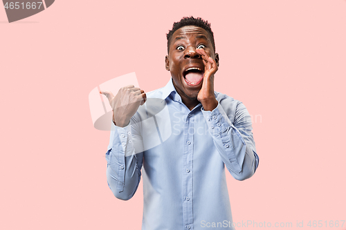 Image of The young man whispering a secret behind her hand over pink background