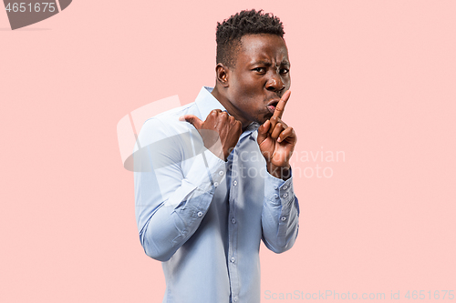 Image of The young man whispering a secret behind her hand over pink background