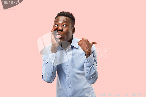 Image of The young man whispering a secret behind her hand over pink background