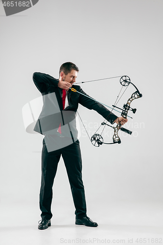 Image of Businessman aiming at target with bow and arrow, isolated on white background