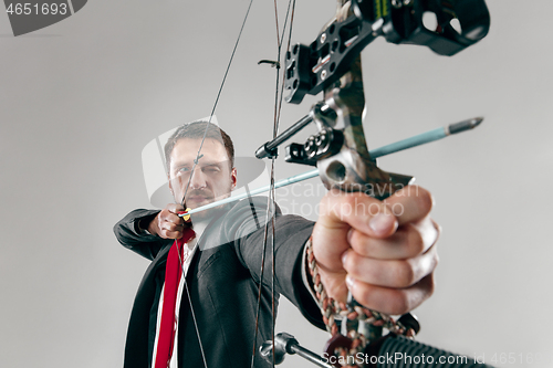 Image of Businessman aiming at target with bow and arrow, isolated on white background