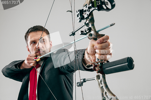 Image of Businessman aiming at target with bow and arrow, isolated on white background