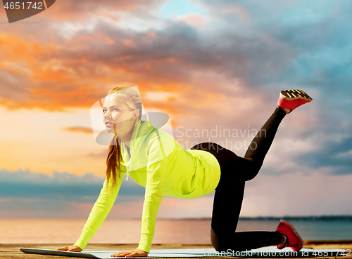 Image of woman training on exercise mat at seaside