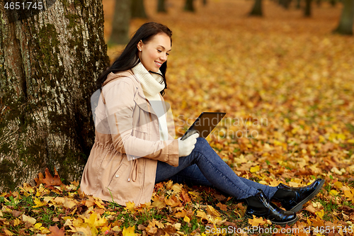 Image of woman with tablet computer at autumn park
